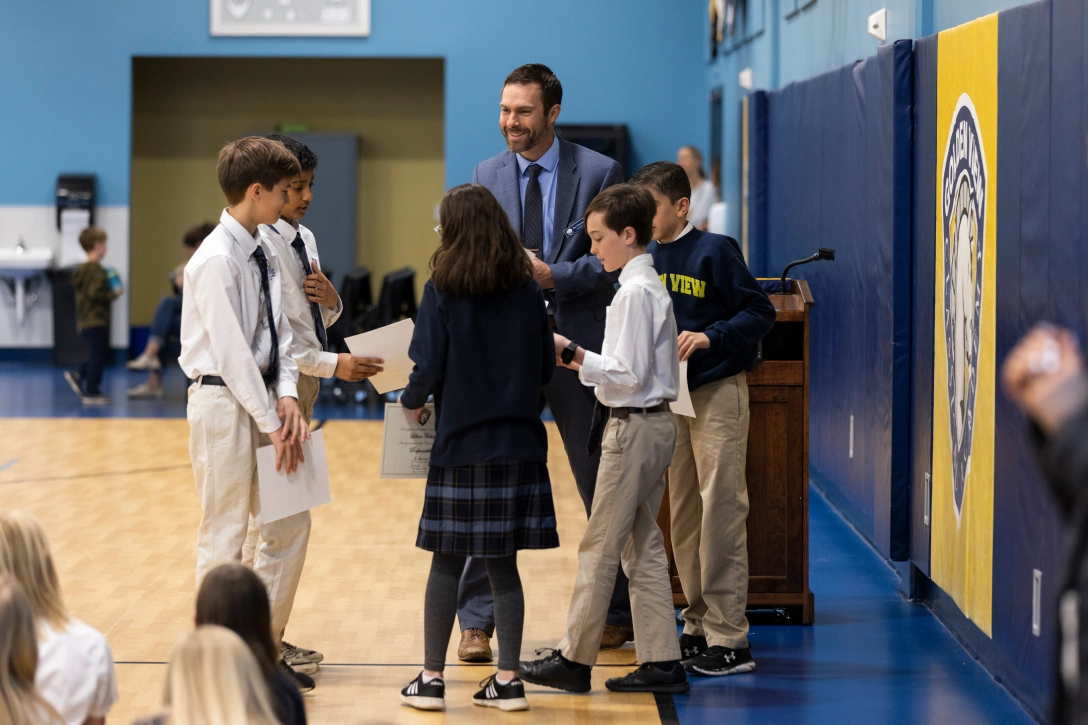 School administrator hands character awards to students.
